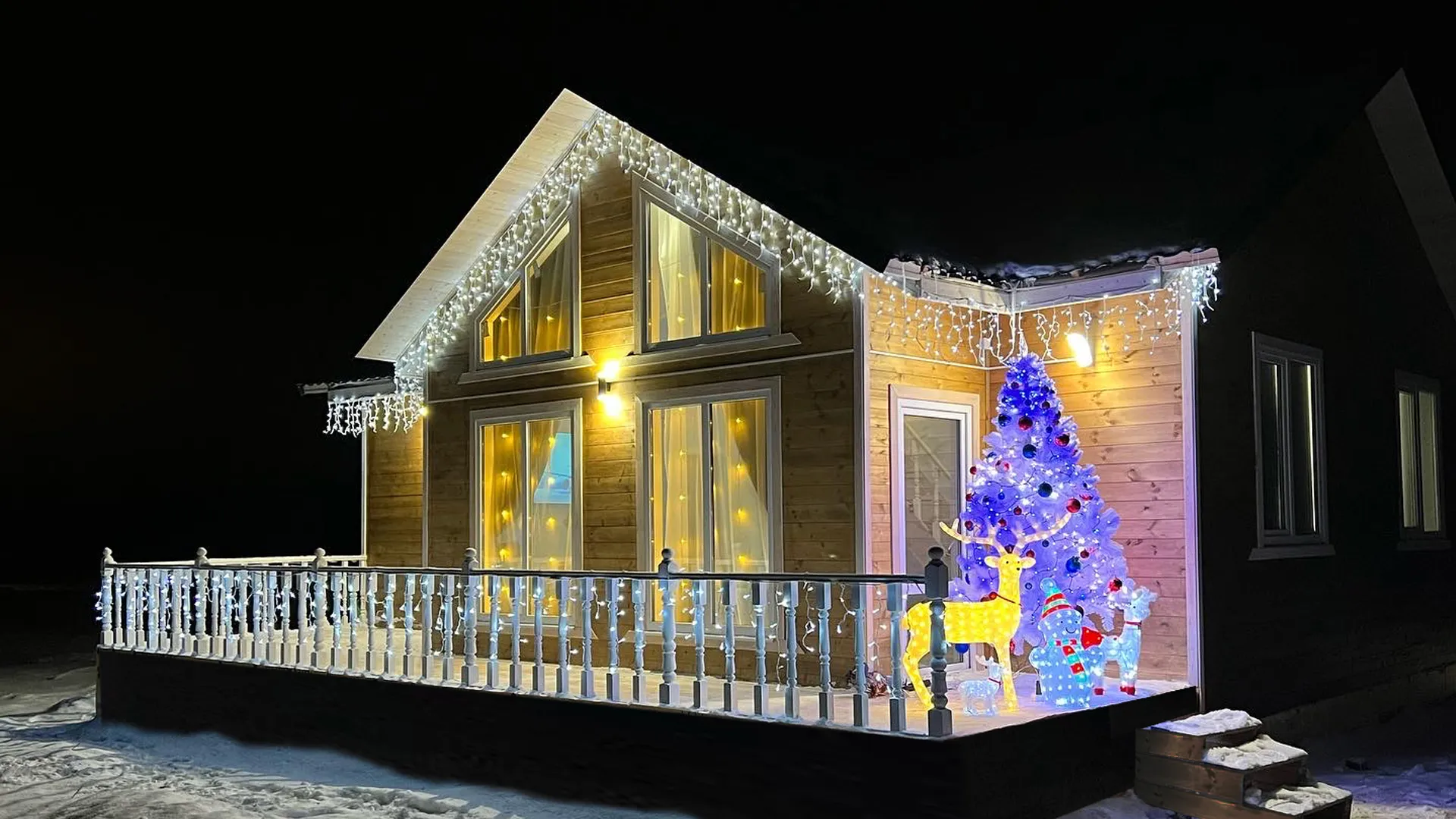 Ночной фасад каркасного дома с подсветкой и террасой в поселке Раздолье